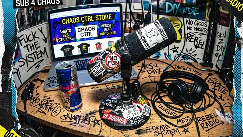 A niche creator desk setup with a podcast microphone, headphones, and a merch storefront on a laptop.